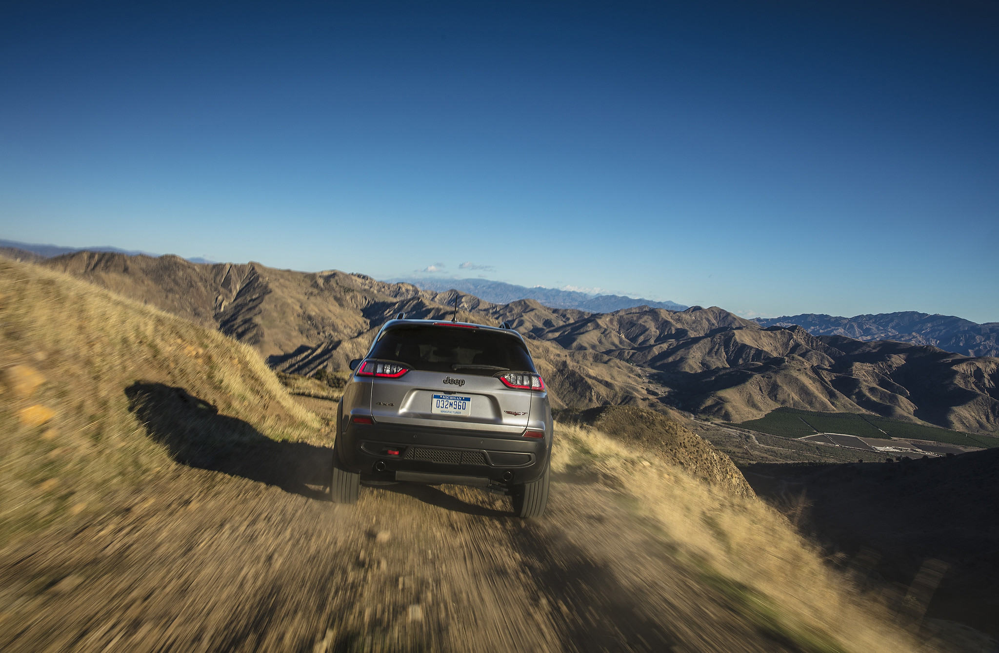 Un Jeep Cherokee Trailhawk 2021 conduisant sur une route de terre montagneuse