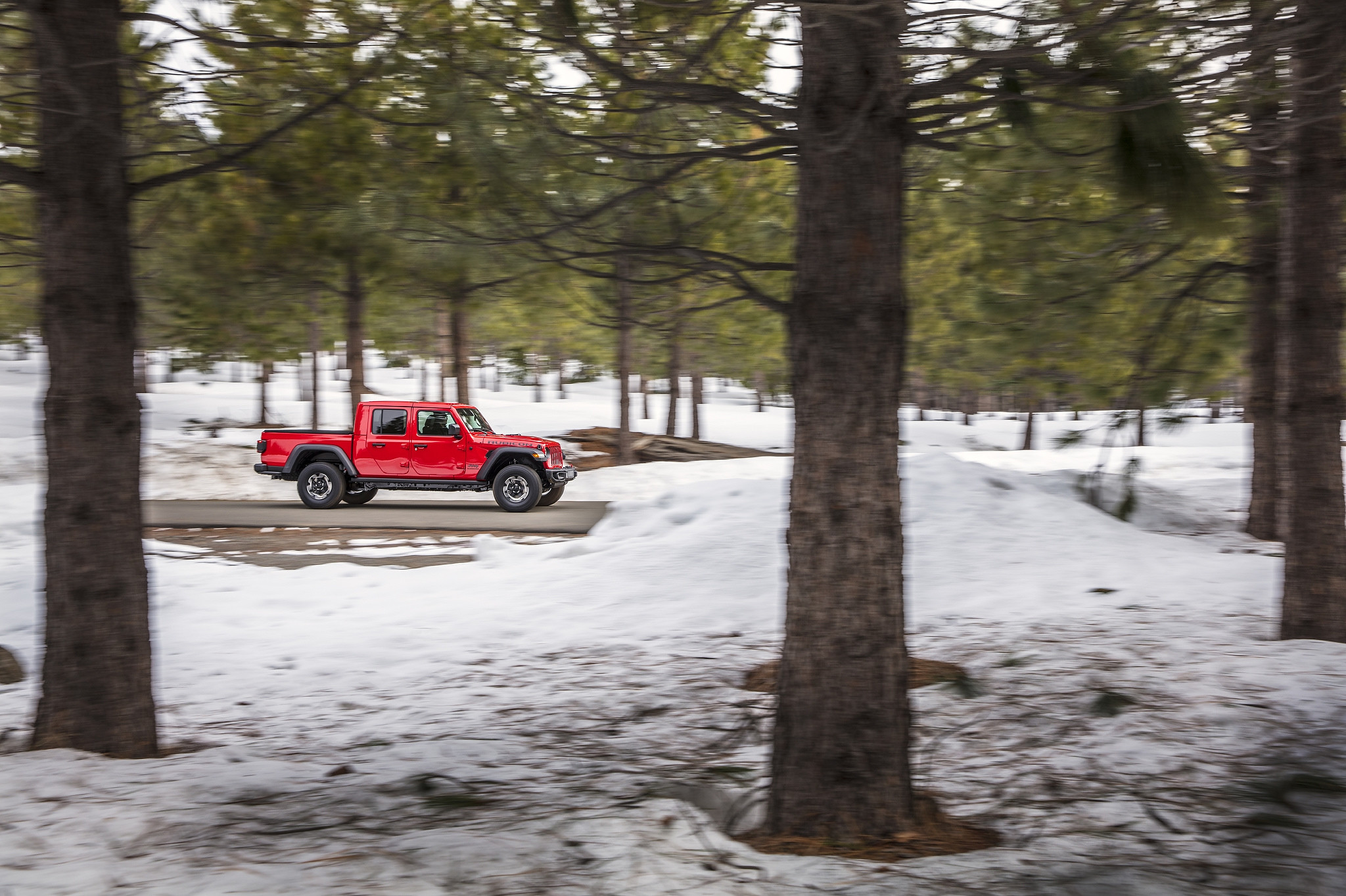 A 2021 Jeep Gladiator Rubicon on a road surrounded by a snow-covered forest