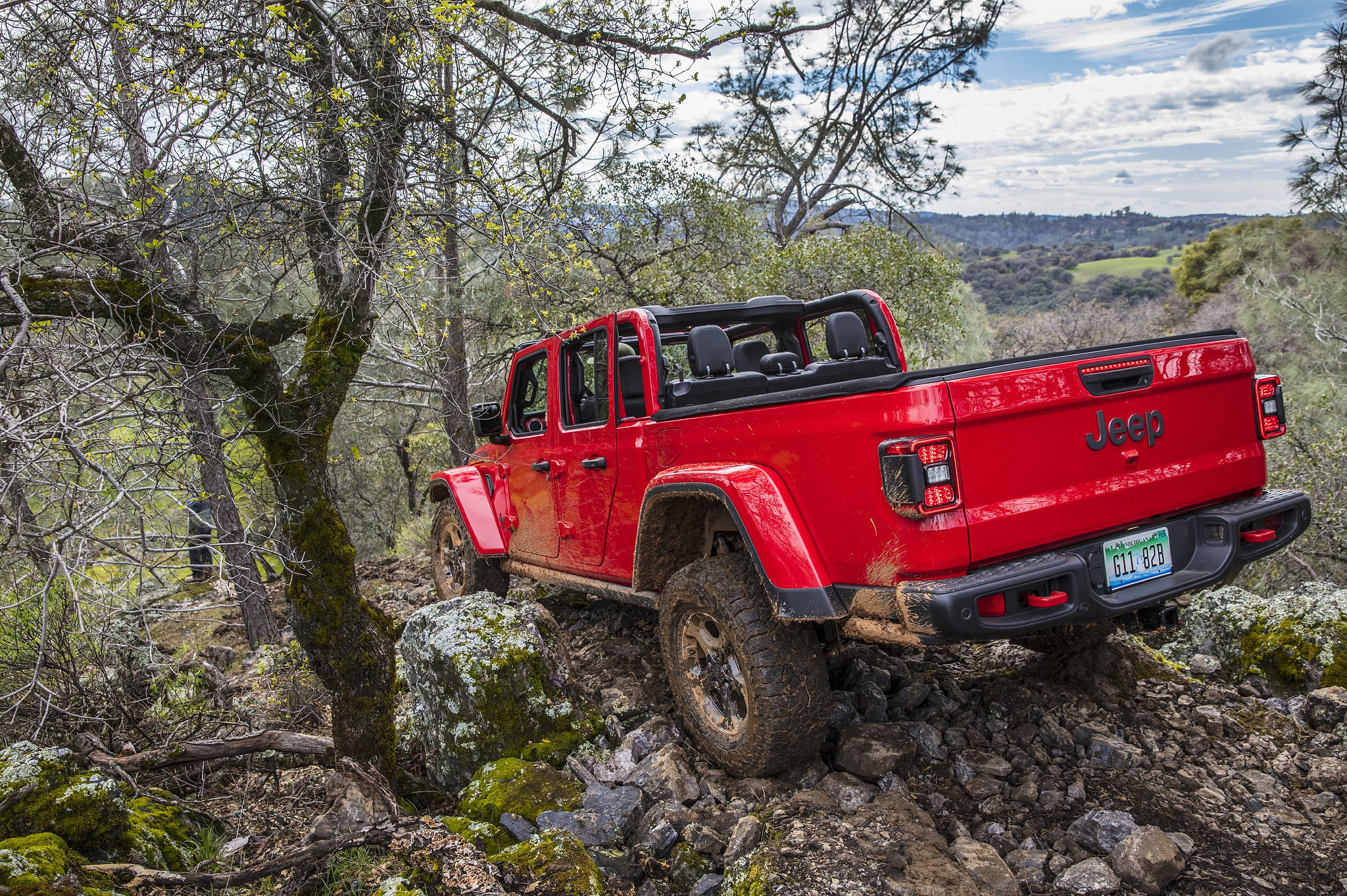 Un Jeep Gladiator Rubicon 2021 faisant face à une pente rocheuse abrupte et surplombant une vallée verdoyante
