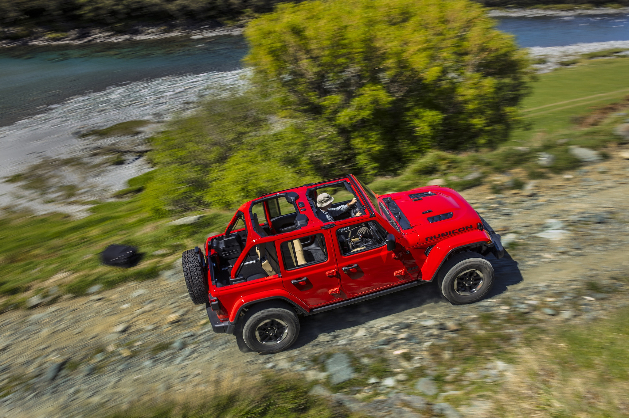 Top view of a 2021 Jeep Wrangler Rubicon driving along a gravel road near a stream
