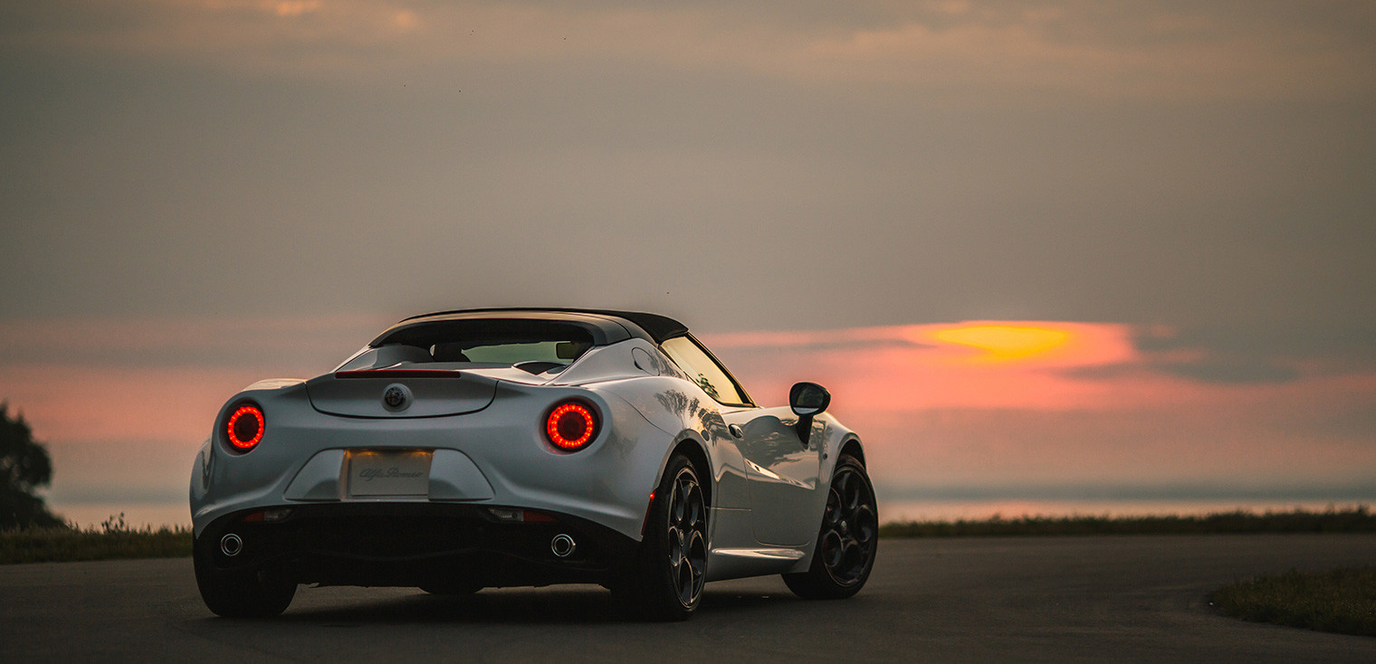 Vue de la custode arrière de l’Alfa Romeo, illustrée avec un extérieur blanc sous le soleil couchant