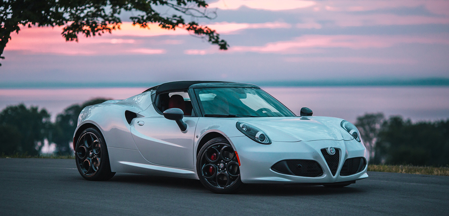 Profil général avant d’une Alfa Romeo 4C Spider blanche sous le soleil couchant