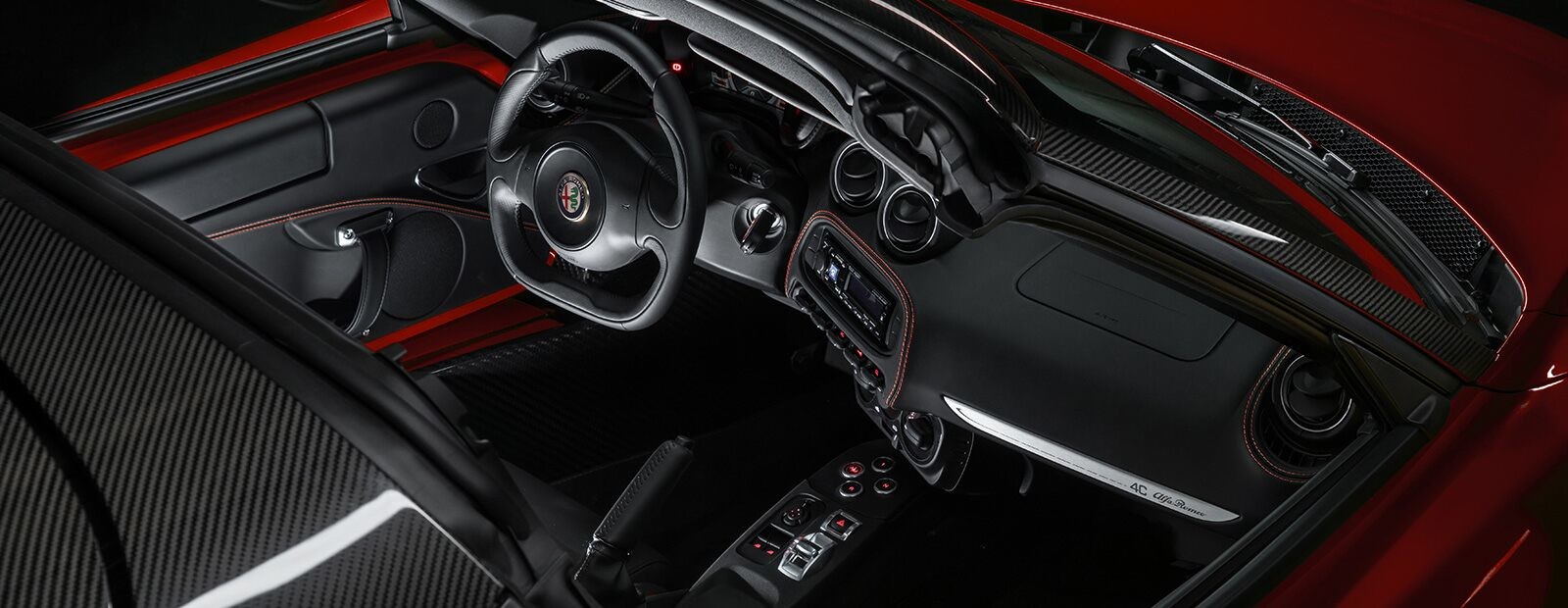 Une vue en plongée de l’Alfa Romeo 4C Spider 2020, la capote baissée, garée près d’un immeuble commercial.