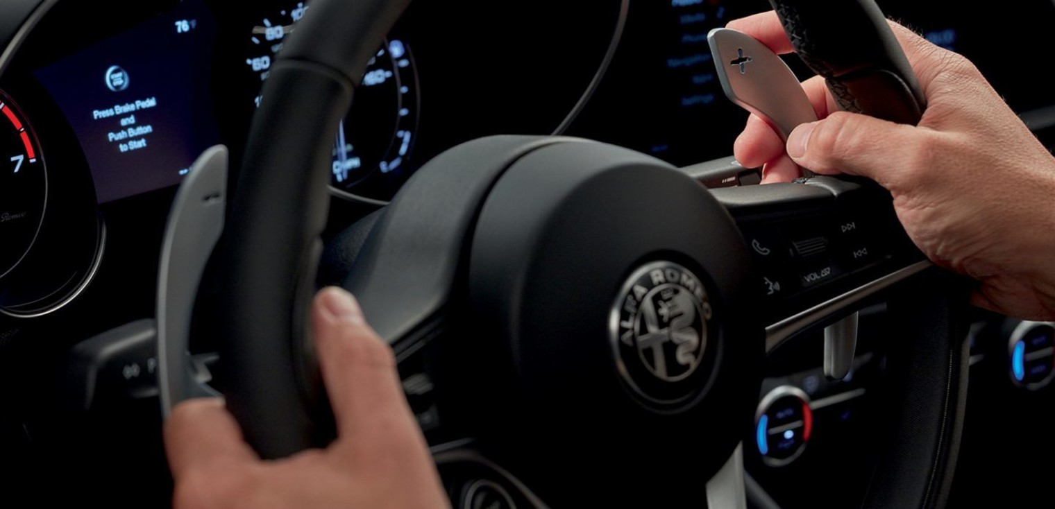The steering wheel of the Alfa Romeo Giulia, showing a driver controlling the paddle shifters