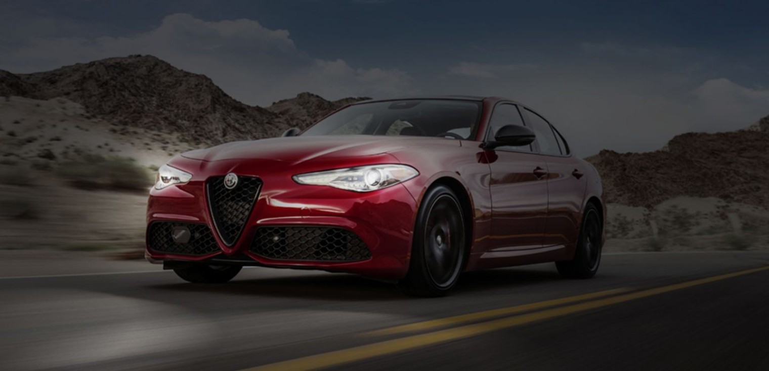 The red 2019 Alfa Romeo Giulia driving on a a highway at night, showcasing the Bi-Xenon headlights