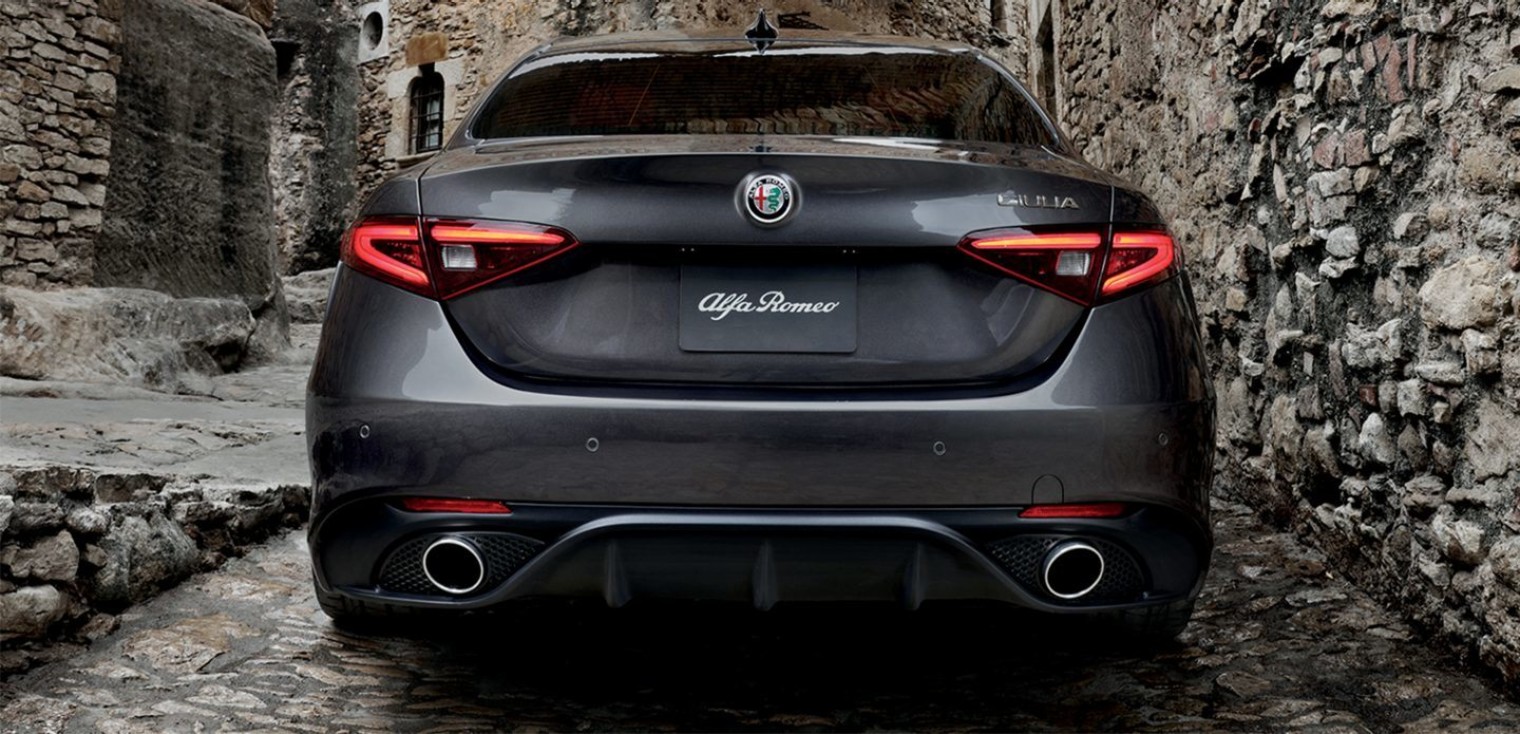 Rear view of the grey 2019 Alfa Romeo Giulia driving down a narrow alleyway