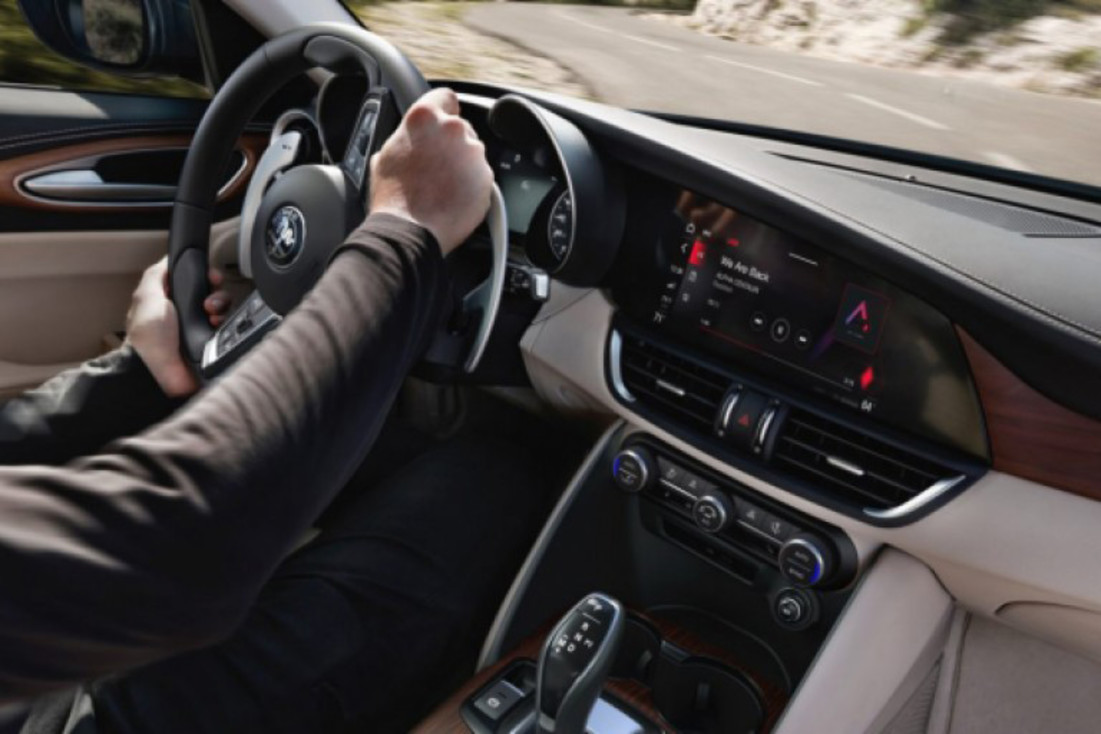 A close-up of the steering wheel, instrument panel, touchscreen and centre console controls in the 2020 Alfa Romeo Giulia.