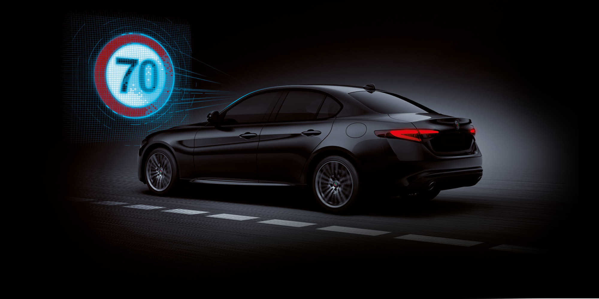 A side view of a black Alfa Romeo Giulia with illustrated blue sensor lines emanating from the windshield towards a 70 km/h speed limit sign.