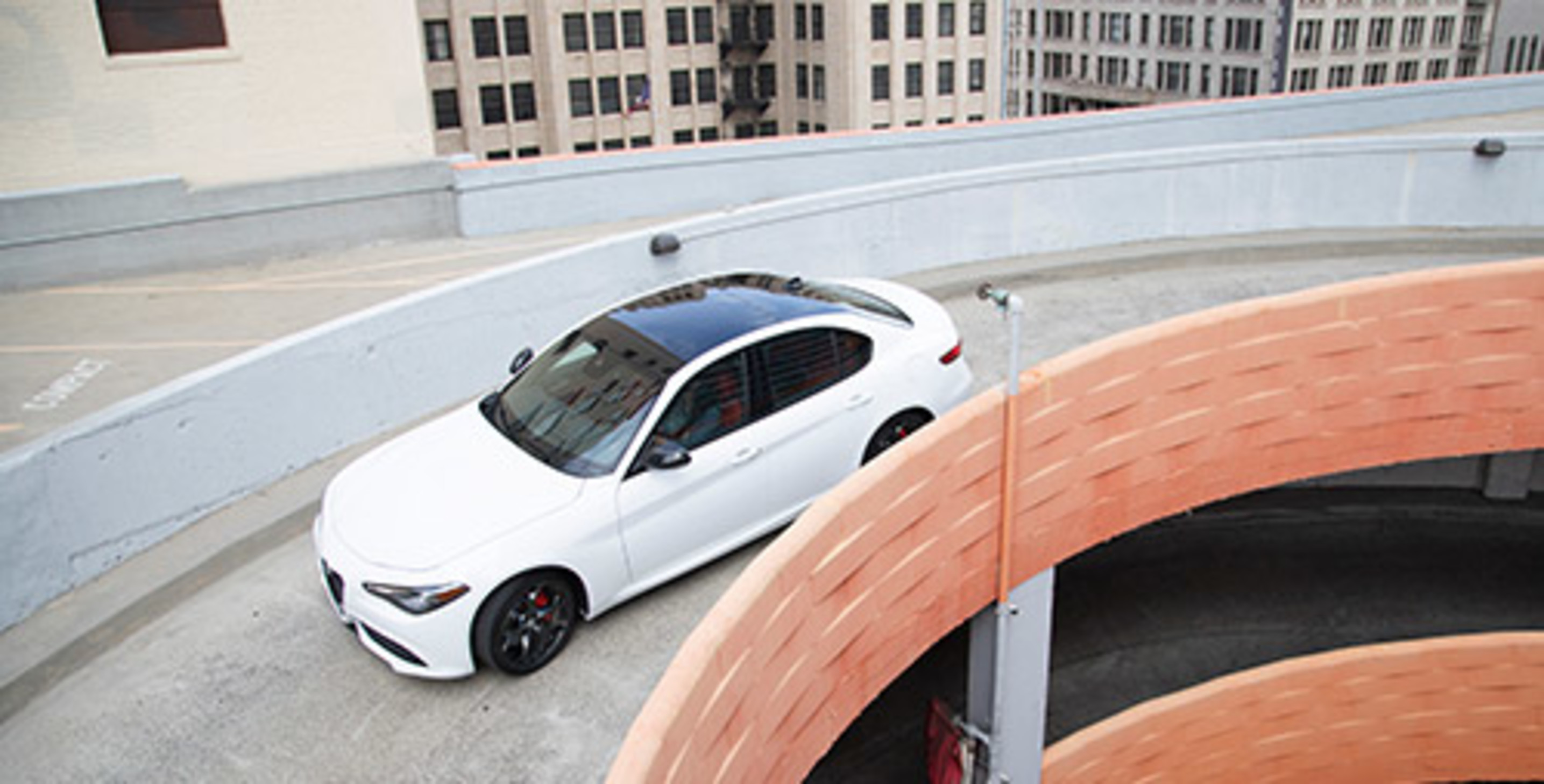 Birds eye view of While 2021 Alfa Romeo Giulia being driven down a parking garage ramp
