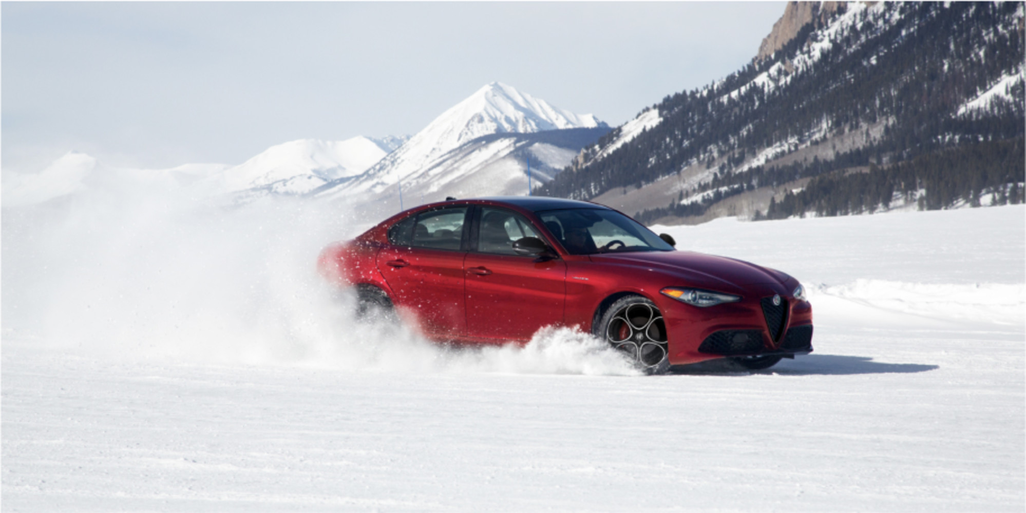 Red Alfa Romeo Giulia driving on snow.