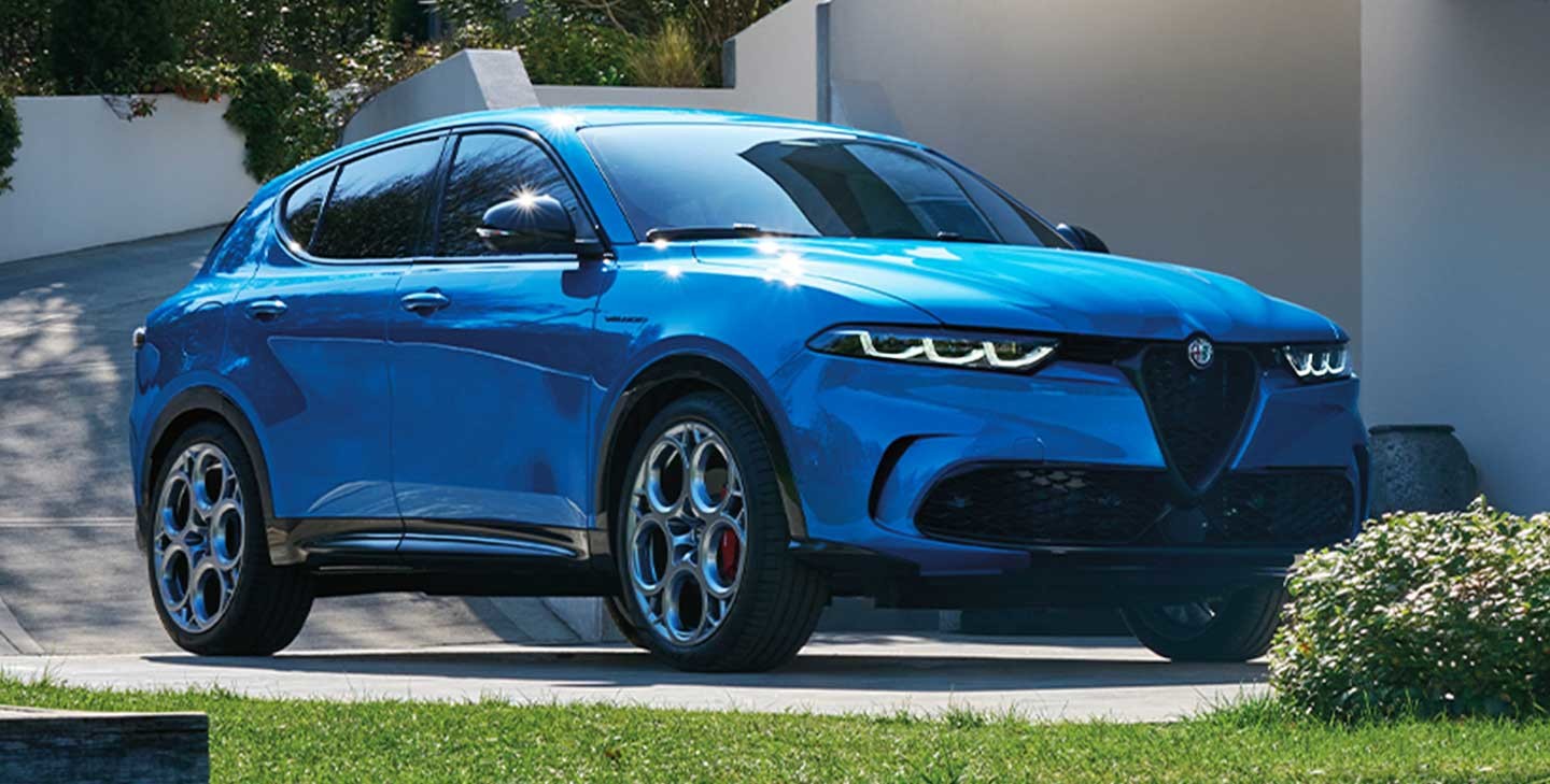 Alfa Romeo Tonale 2024 bleue stationnée dans une allée moderne, entourée de verdure et de bâtiments contemporains.