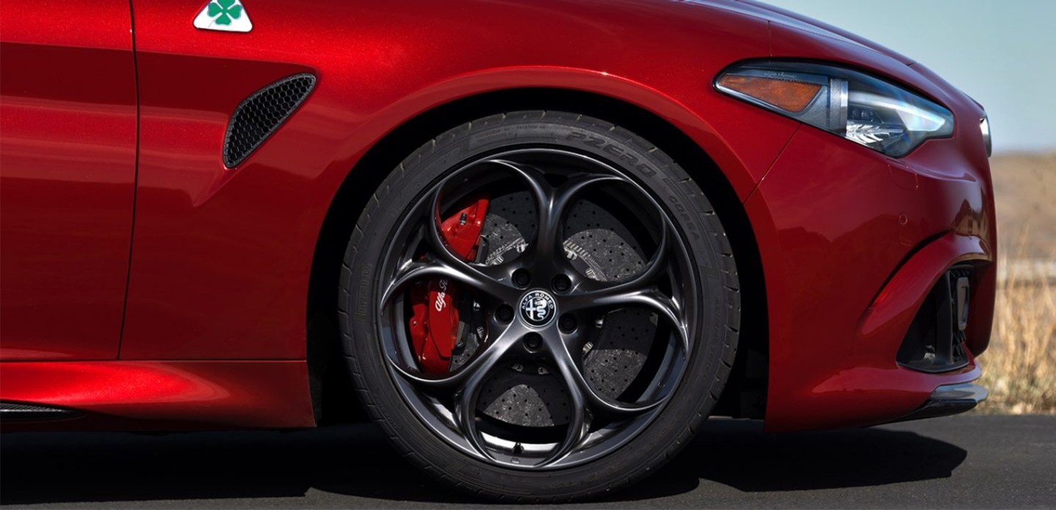 Side view of the red 2019 Alfa Romeo Giulia Quadrifoglio showing its front fender and dark 5-hole aluminum wheels