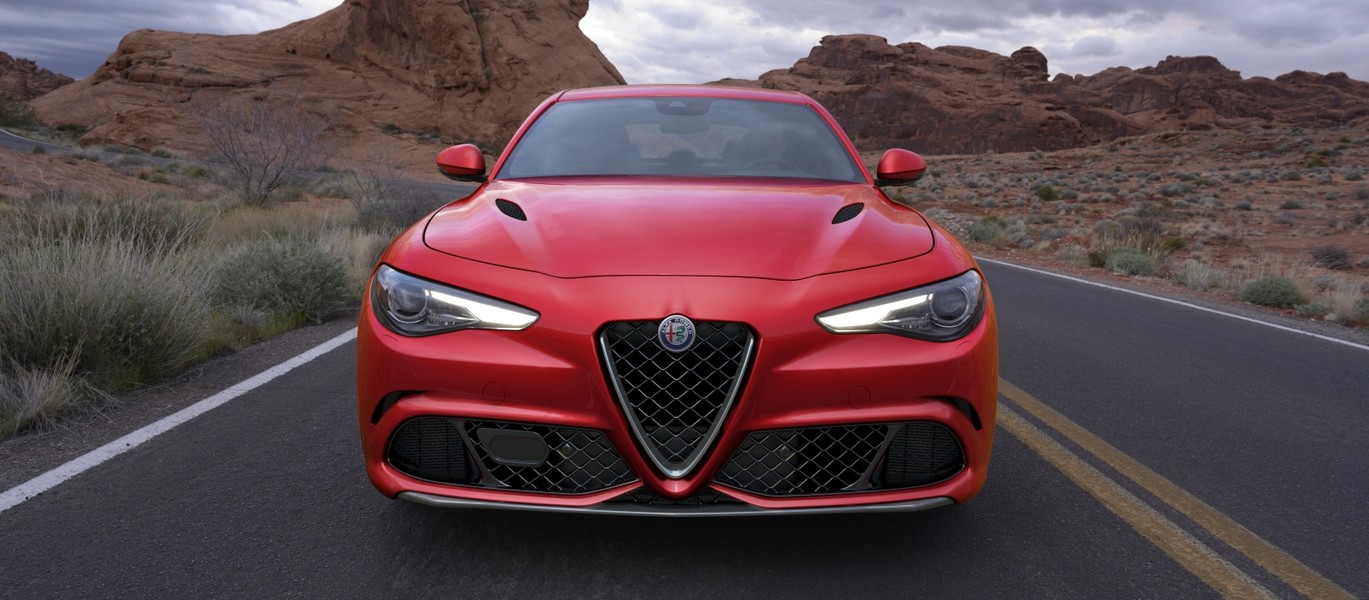 2021 Alfa Romeo Giulia Quadrifoglio in red, driving on a road in the desert.
