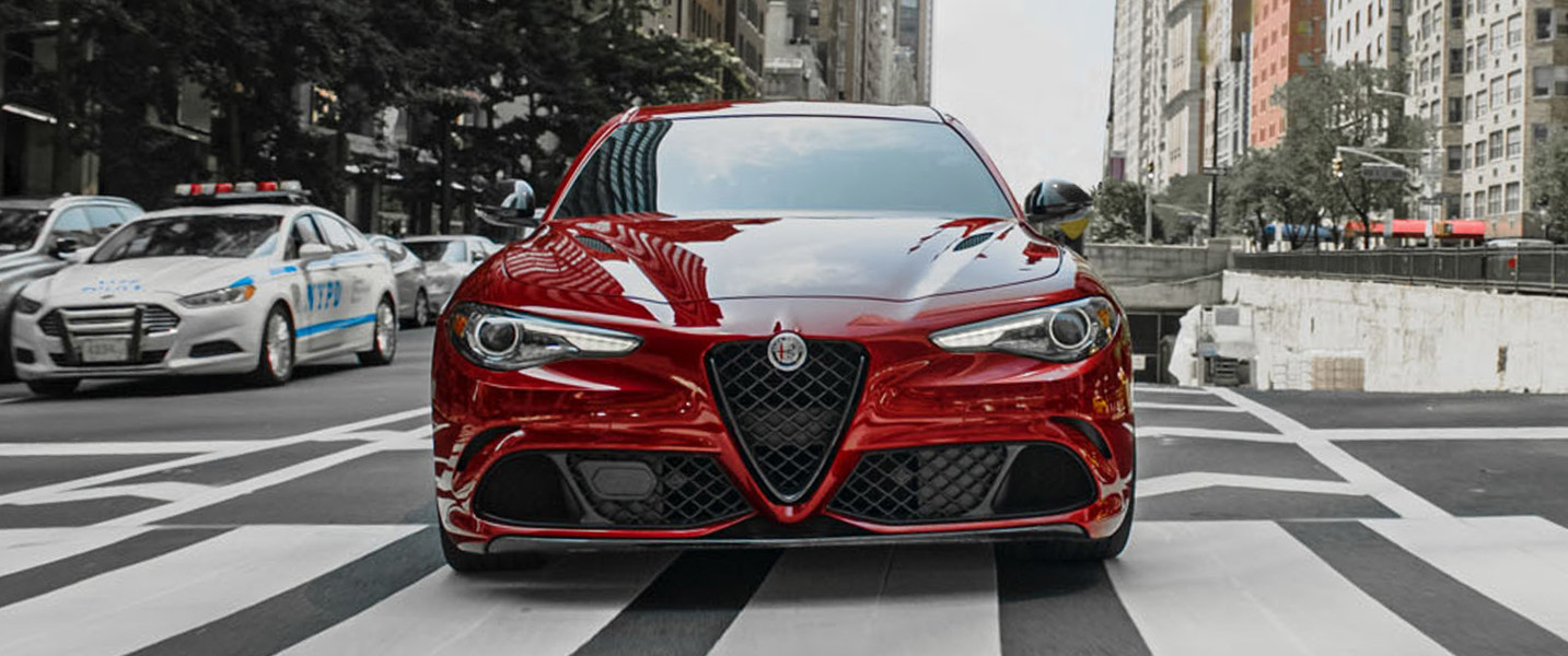 Une Alfa Romeo Giulia Quadrifoglio rouge garée sur un passage clouté dans une ville
