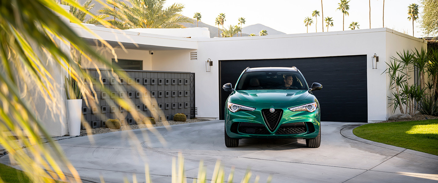 Front view of a green Alfa Romeo Stelvio Quadrifoglio parked in a driveway.