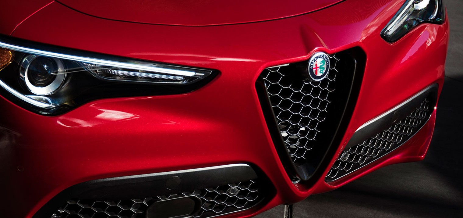 Vue de face de l’Alfa Romeo Stelvio 2019, illustré en rouge, montrant les phares bixénon et la calandre Scudetto