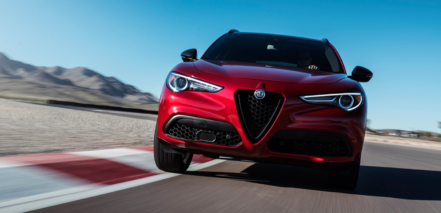 Vue de face de l’Alfa Romeo Stelvio 2019, illustré en rouge, roulant sur un circuit