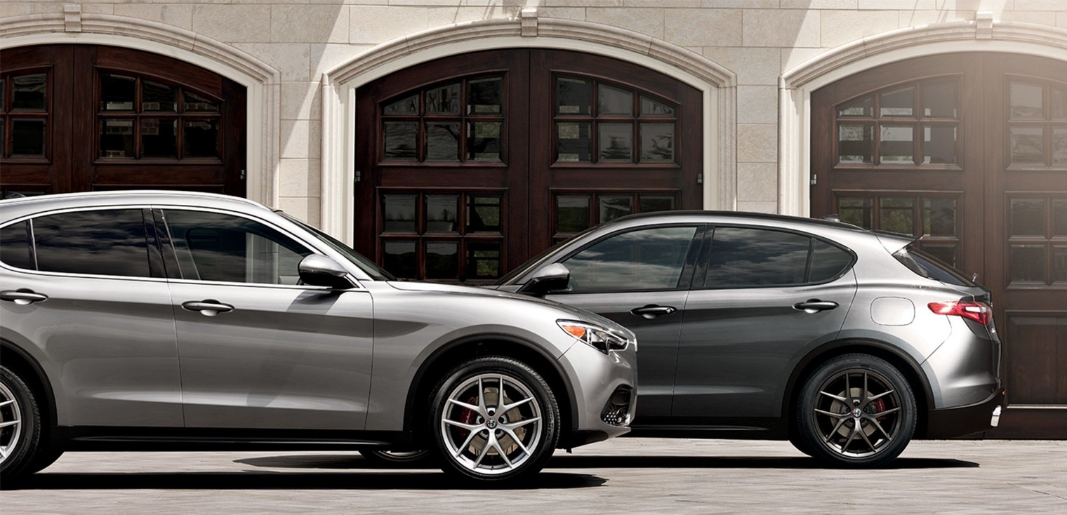 Deux Alfa Romeo Stelvio 2019, illustrés en argent, stationnés dans une entrée devant un garage