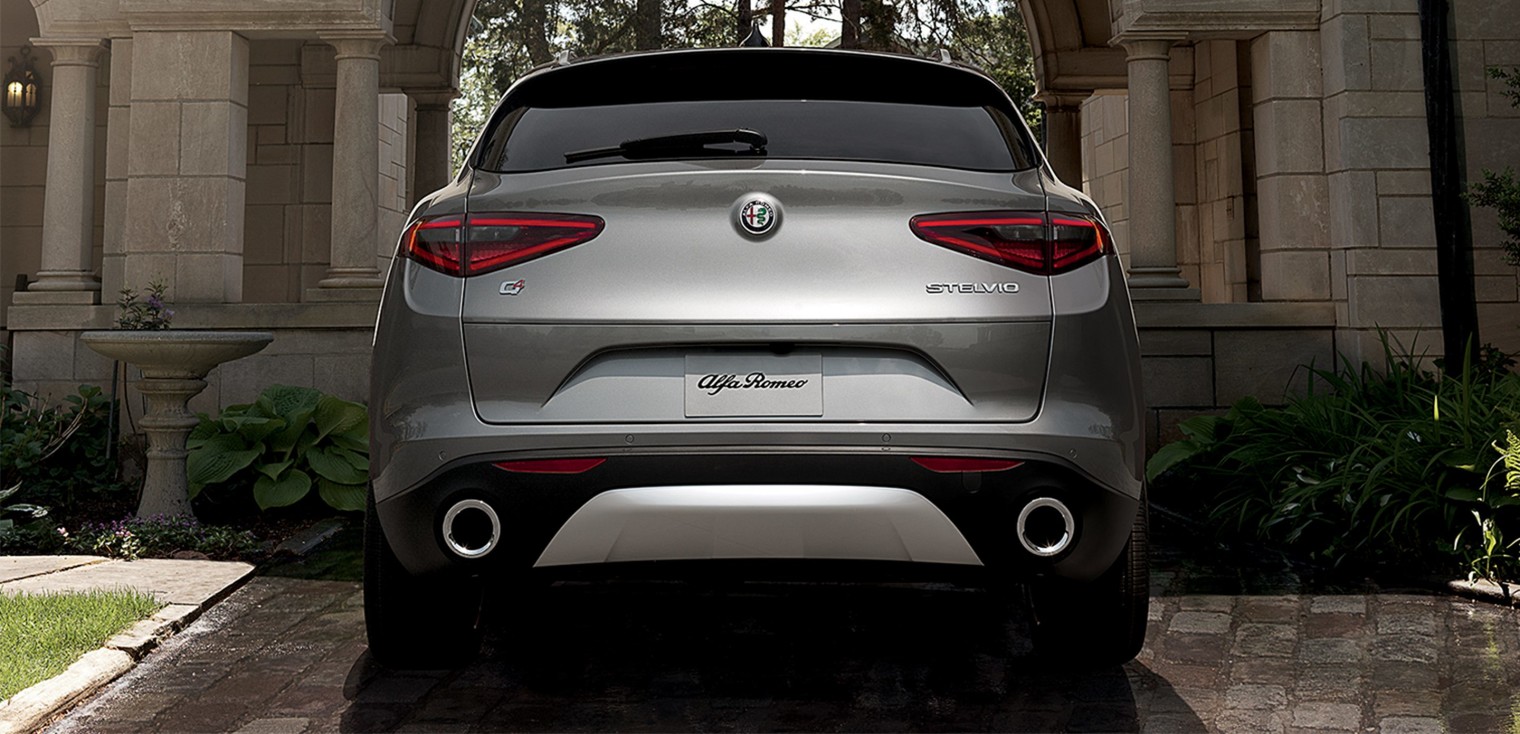 Vue arrière de l’Alfa Romeo Stelvio 2019, illustré en argent, stationné dans une entrée devant un manoir