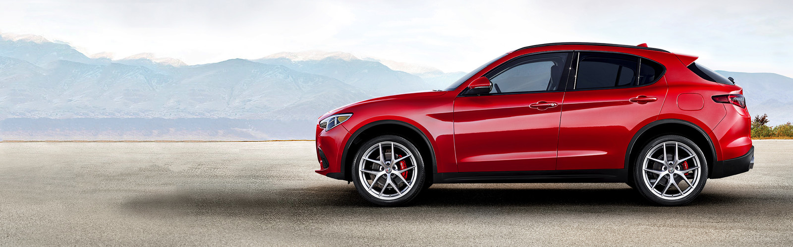 Red 2019 Alfa Romeo Stelvio, parked outdoors with mountains in the background.