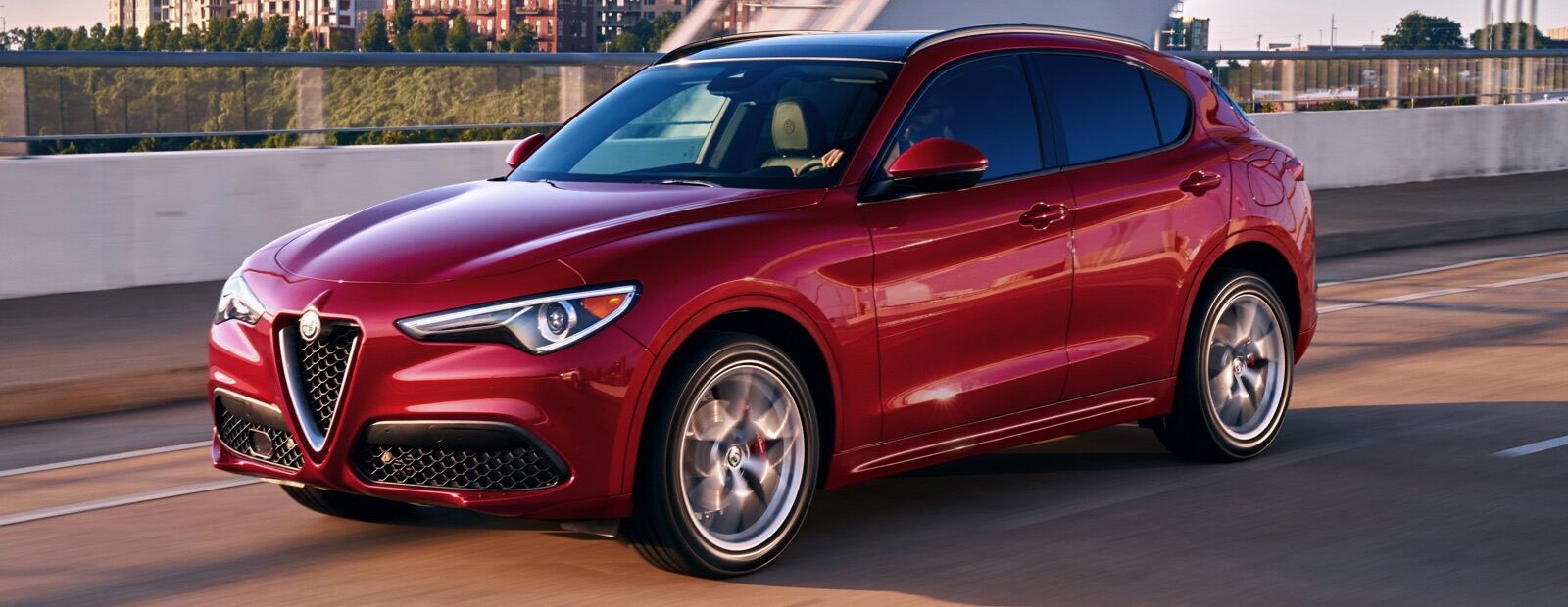 A three-quarter side view of a 2020 Alfa Romeo Stelvio being driven over a bridge.