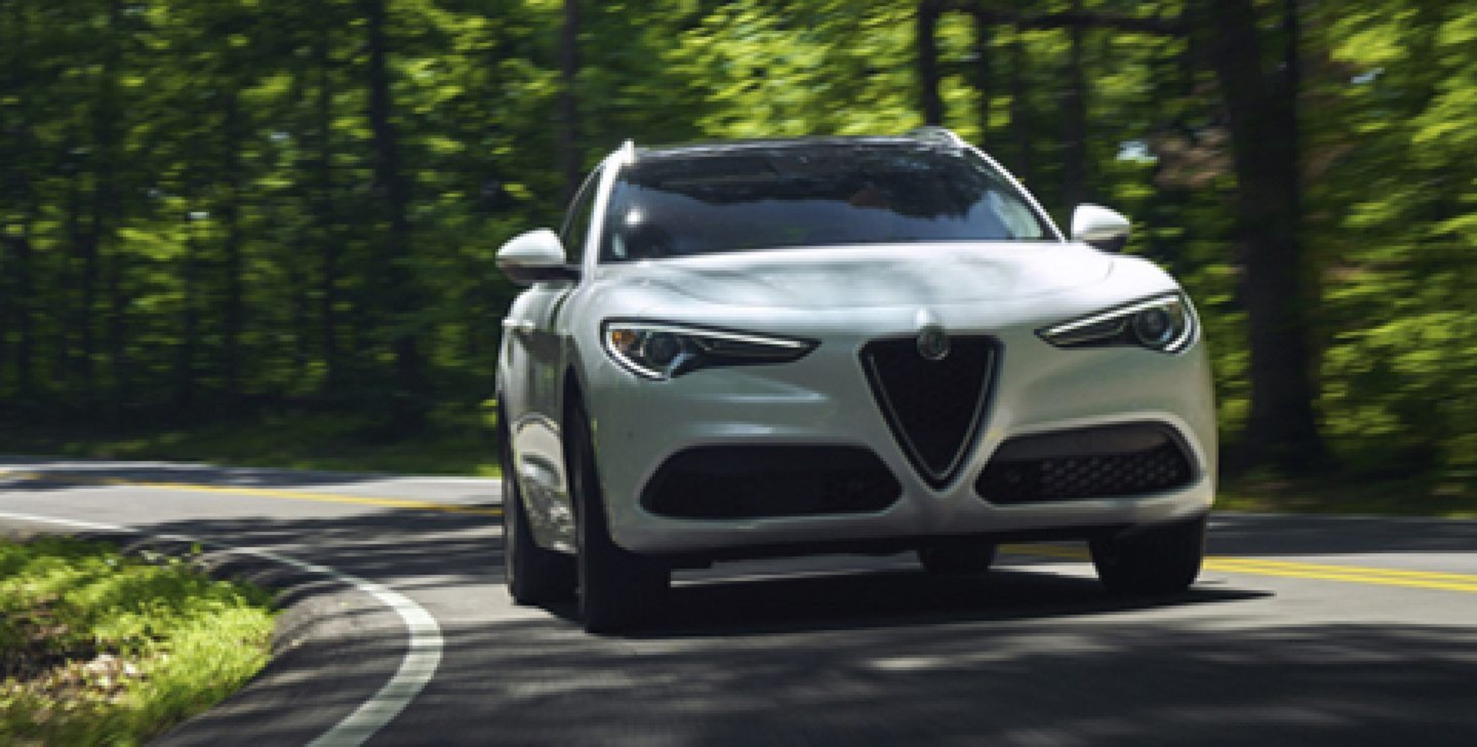 A front view of the 2020 Alfa Romeo Stelvio rounding a curve in the road.