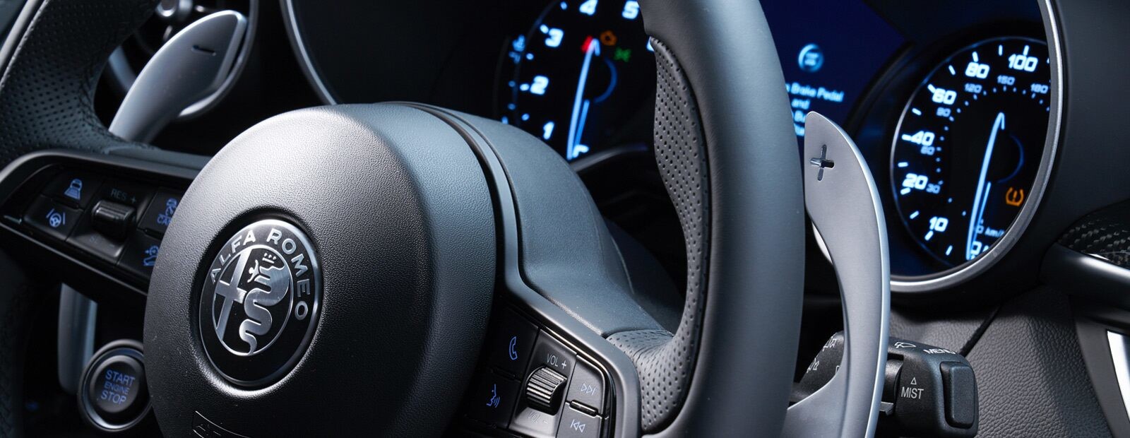 A close-up of the steering wheel in the 2020 Alfa Romeo Stelvio, focusing on one of the paddle shifters.