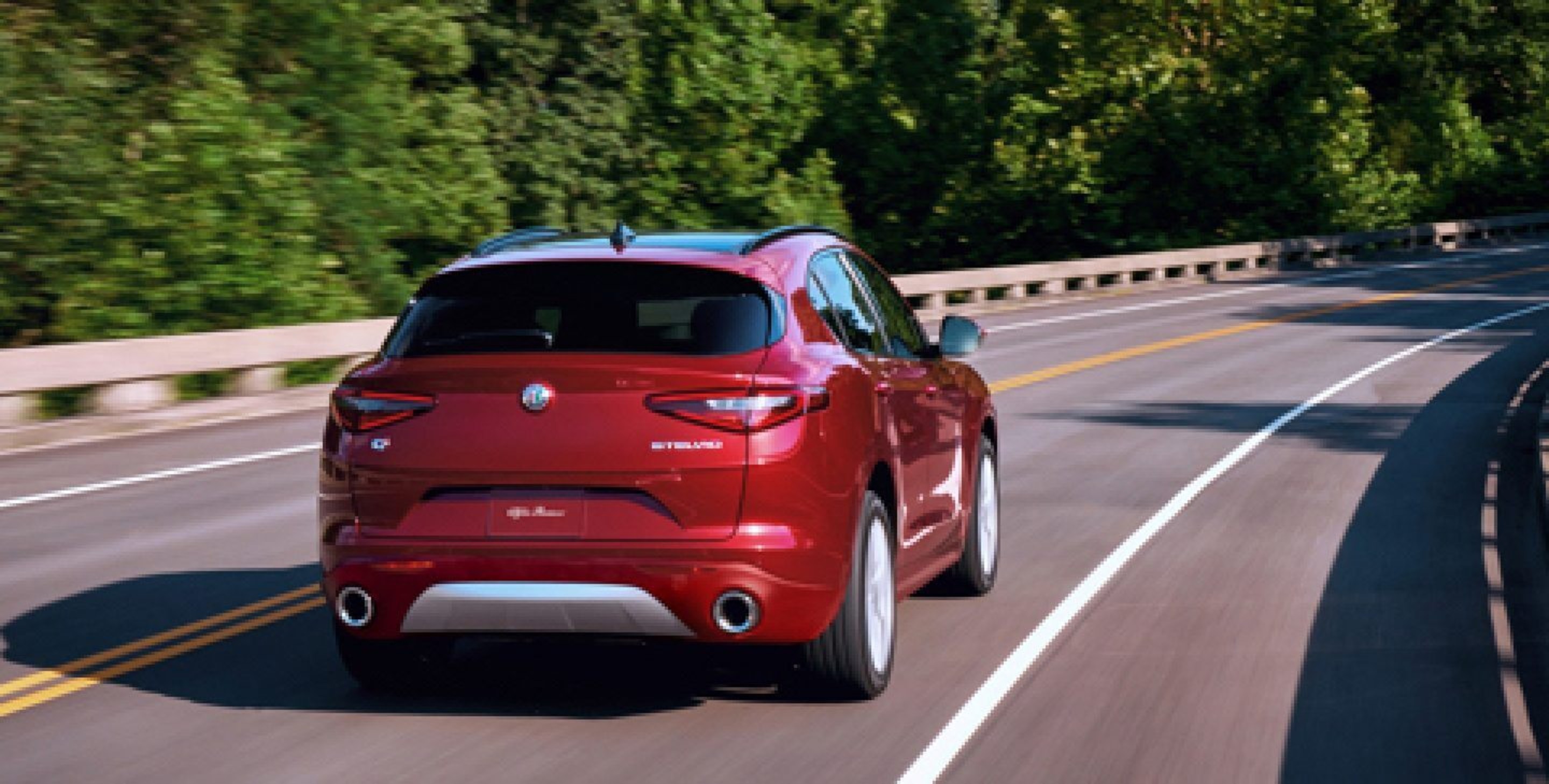 A rear view of the 2020 Alfa Romeo Stelvio being driven across a bridge.