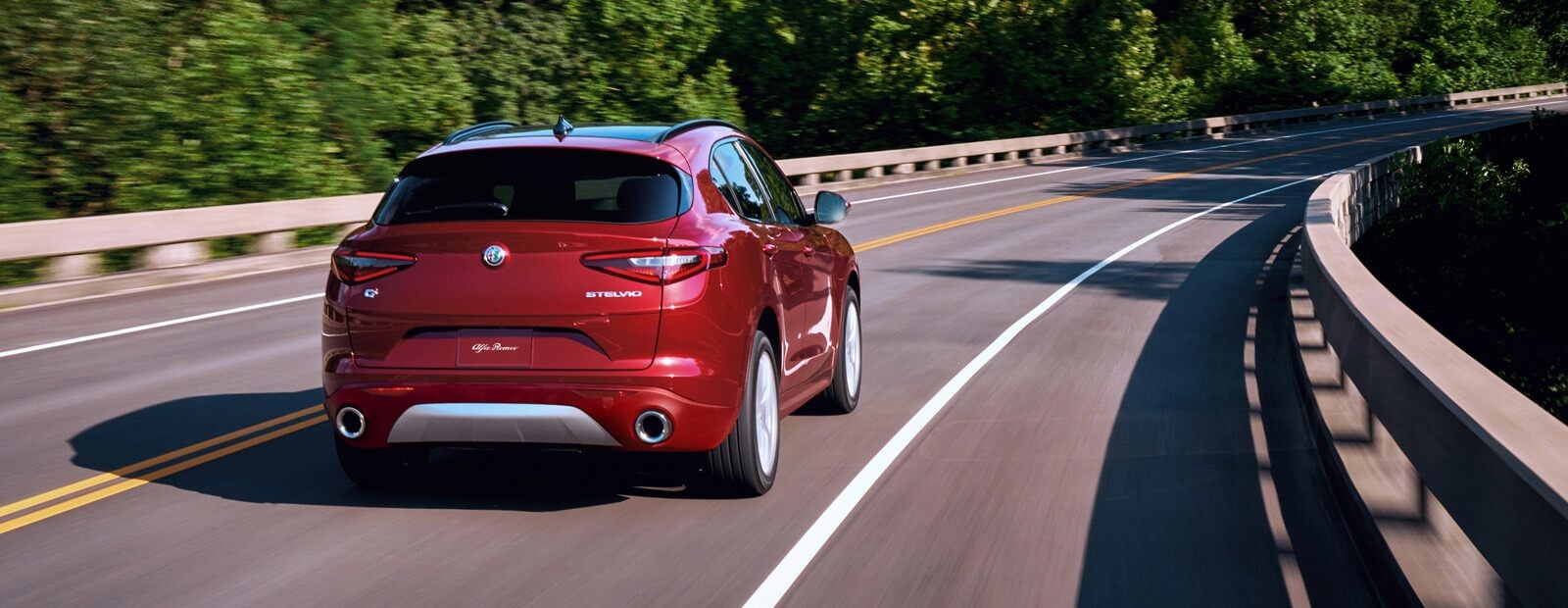 A rear view of the 2020 Alfa Romeo Stelvio being driven across a bridge.