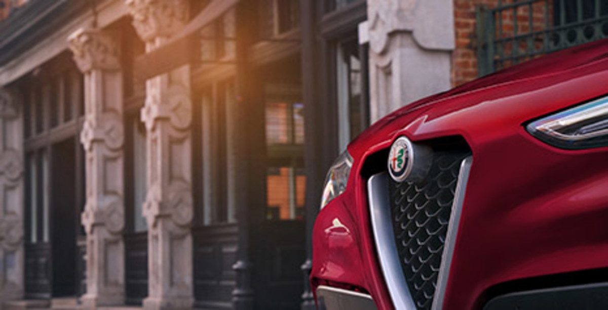 A close up of the front logo of a red 2021 Alfa Romeo Stelvio
