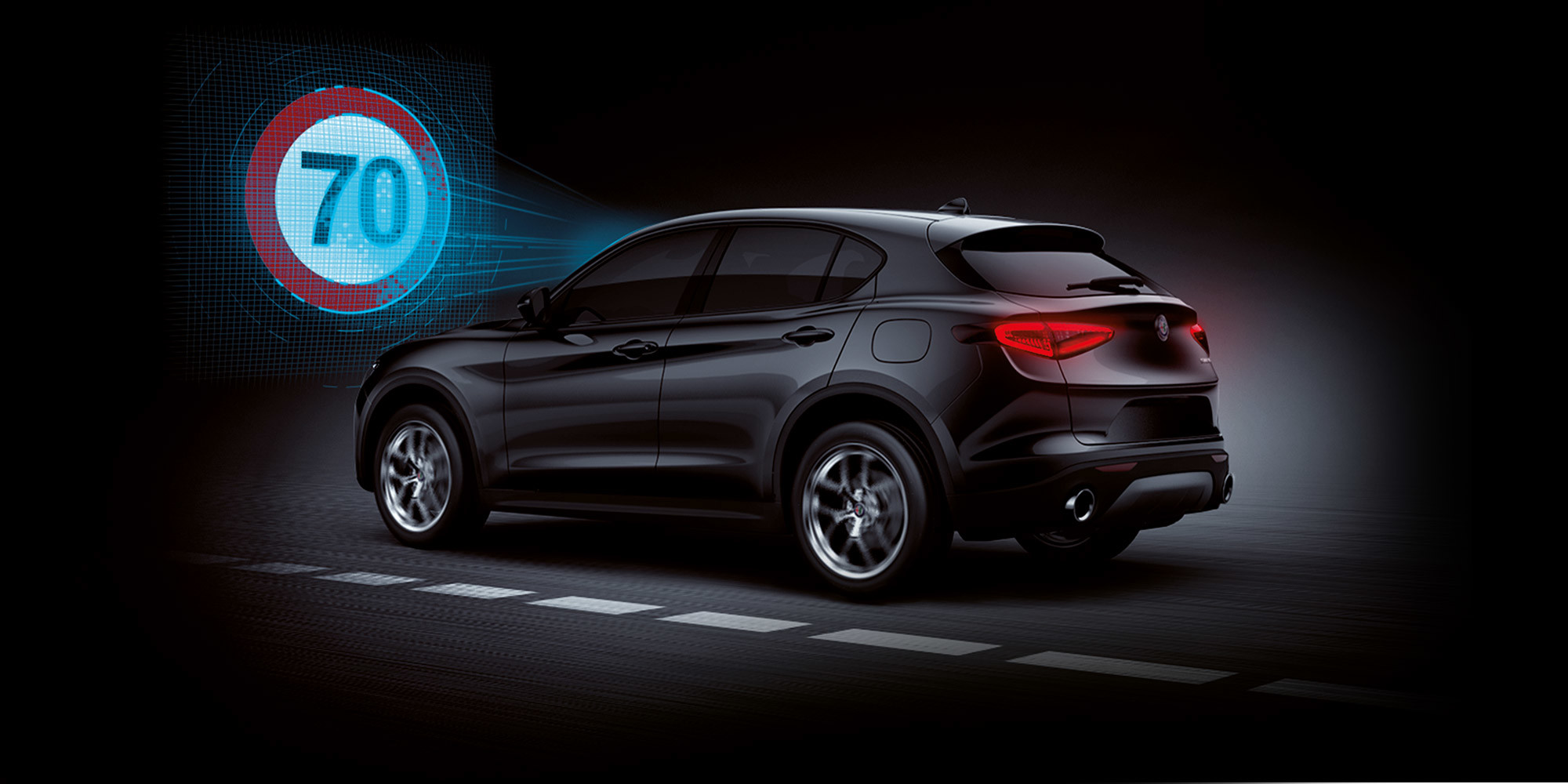 A side view of a black Alfa Romeo Stelvio with illustrated blue sensor lines emanating from the windshield towards a 70 km/h speed limit sign.