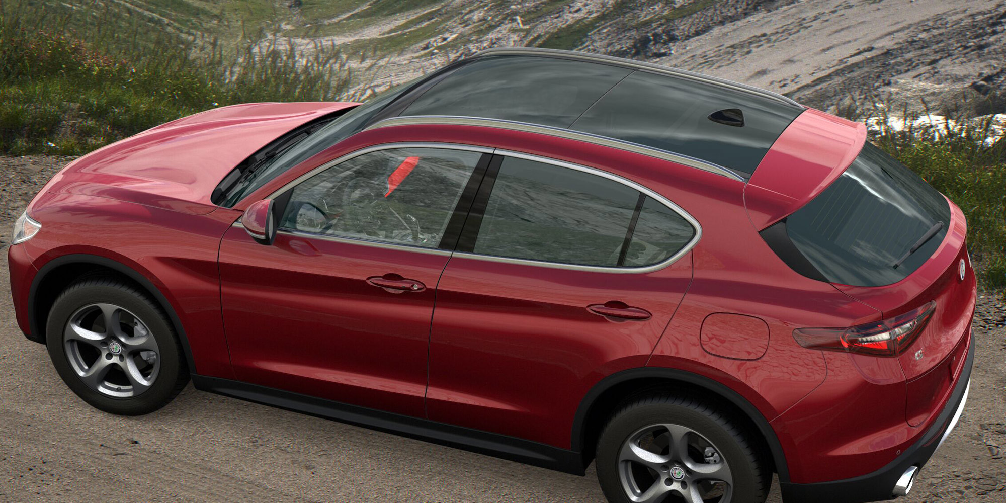 Bird's eye view of a Red 2021 Alfa Romeo Stelvio with a panoramic sunroof parked uphill on a dirt road overlooking a valley