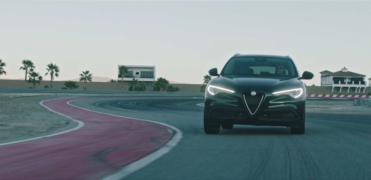 Une vue de l’Alfa Romeo Stelvio 2021 avec les phares à DEL allumés, sur une piste de course.
