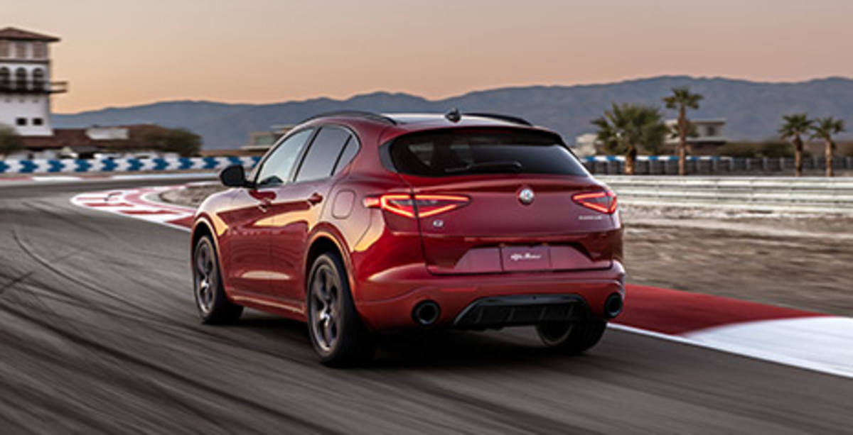 Back view of a red Alfa Romeo Stelvio, driving on the race track.
