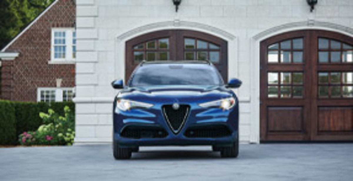 A front view of an Alfa blue 2022 Alfa Romeo Stelvio parked in front of the garage.
