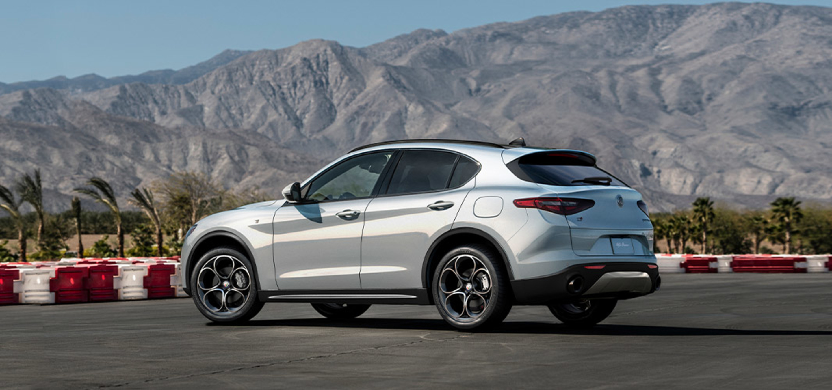 Side view of a white Alfa Romeo Stelvio on a race track.