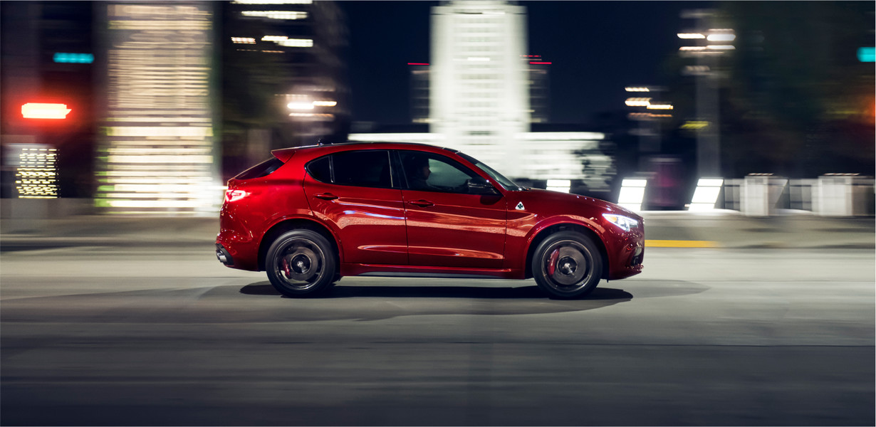 A red 2022 Stelvio driving down a city road