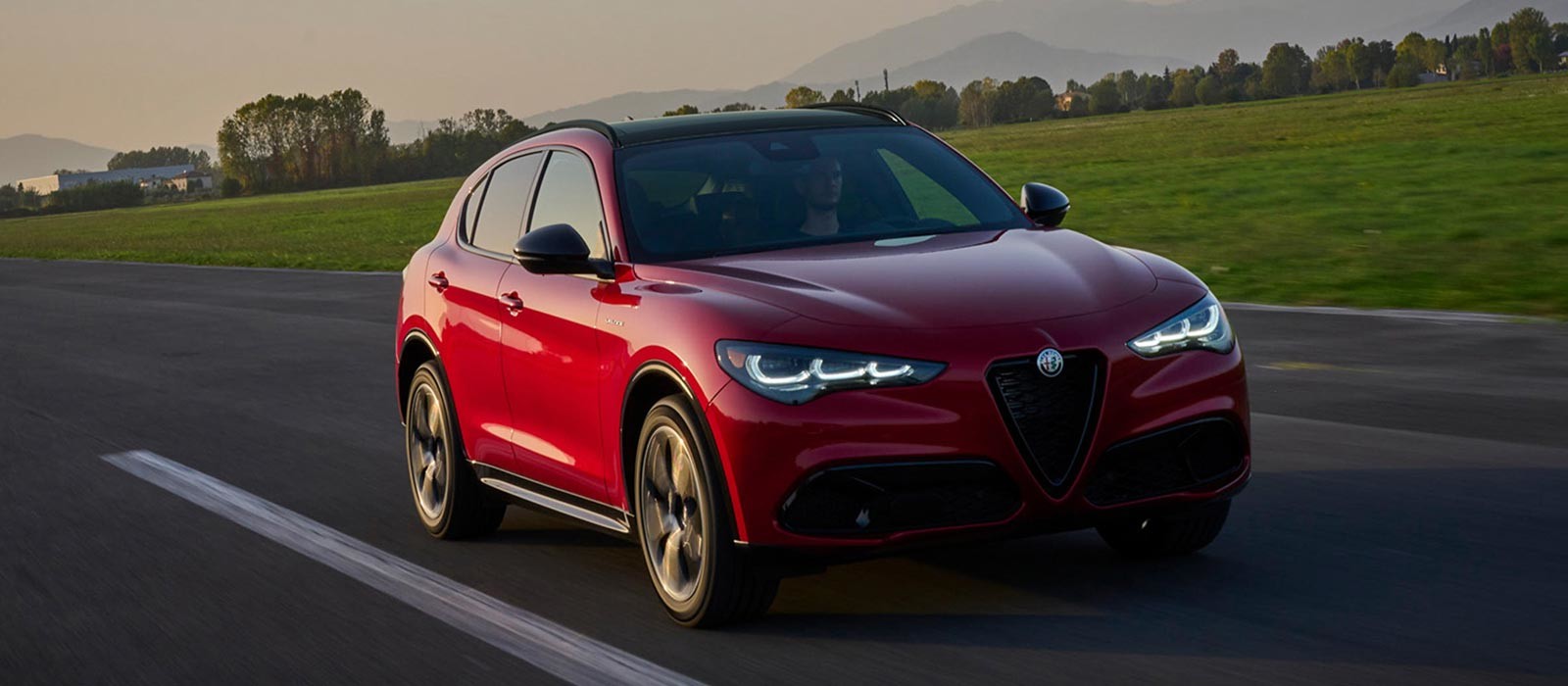 Vue de face d'une Alfa Romeo Stelvio 2025 rouge vue en train de rouler sur une route pavée.