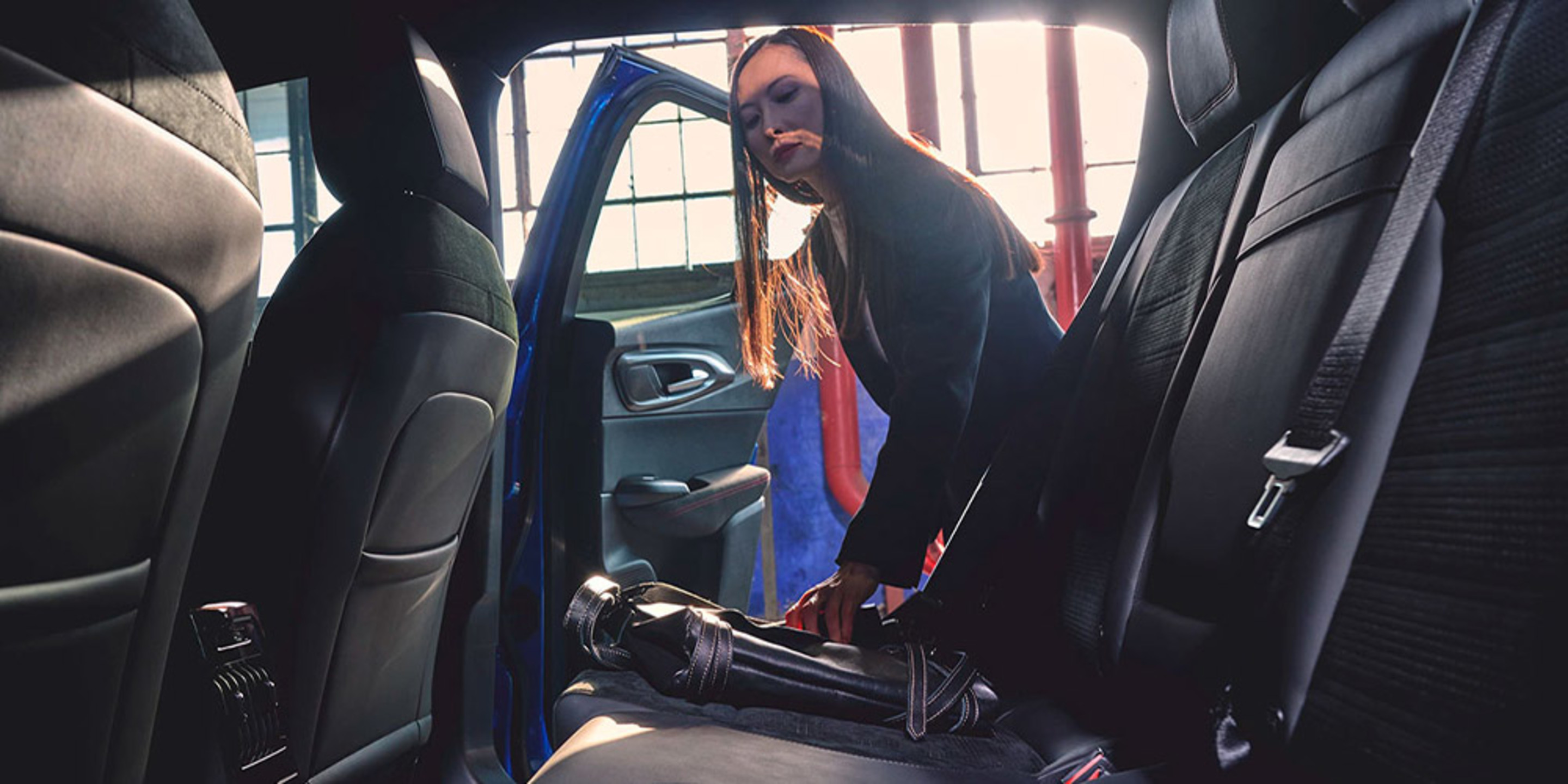 View of a woman near an open back door of an Alfa Romeo Tonale, checking the back seat.