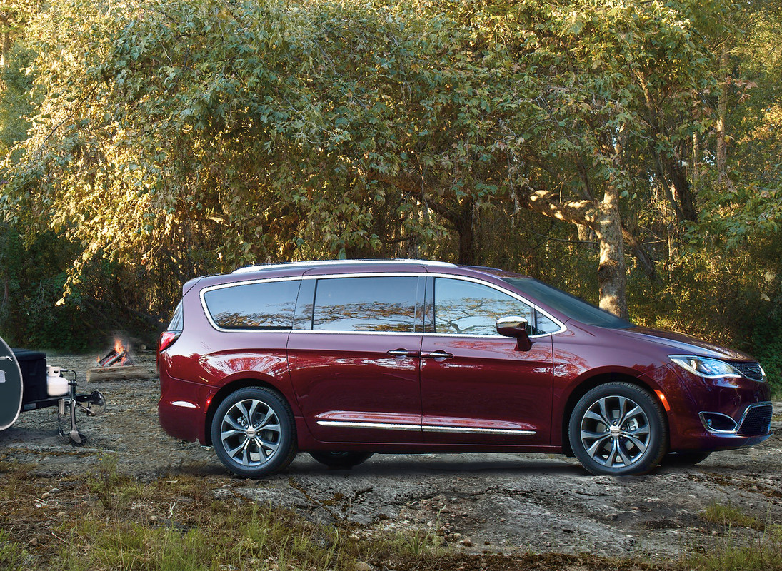 Red 2020 Chrysler Pacifica towing a small RV through the woods.
