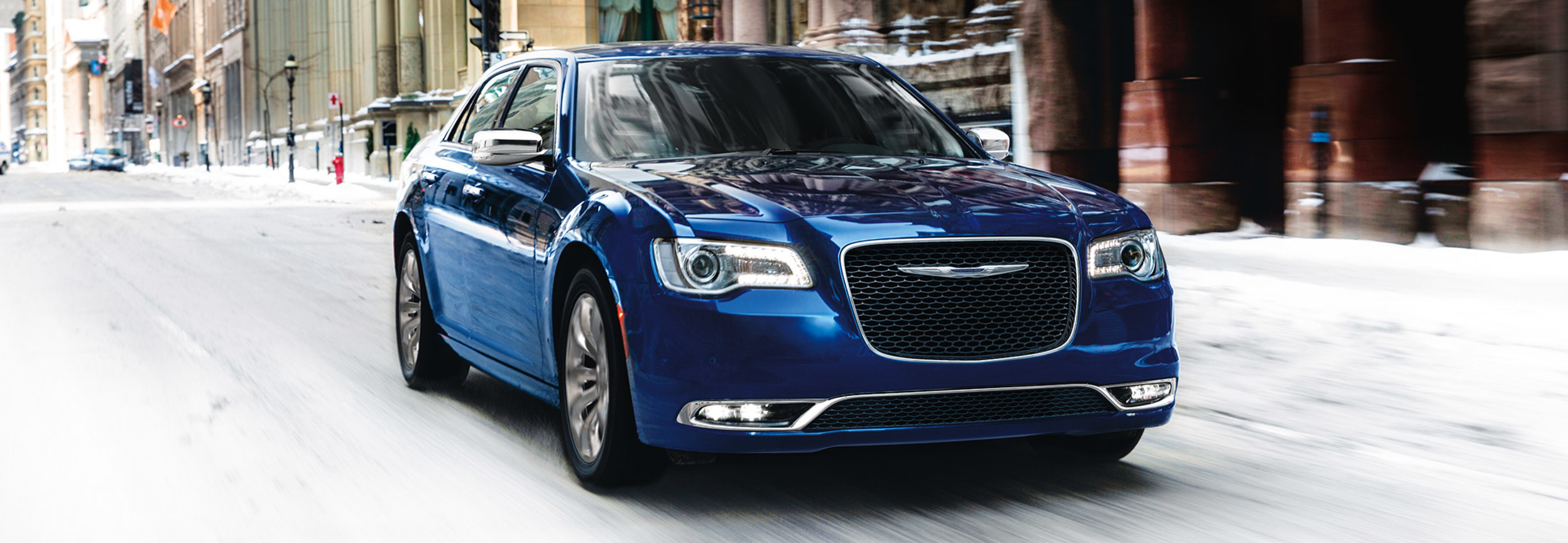 Blue 2020 Chrysler 300 being driven fast through the city in the winter