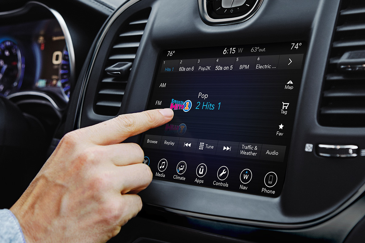 Multimedia system of the 2020 Chrysler 300 while man is touching the screen while Sirius XM radio screen is on