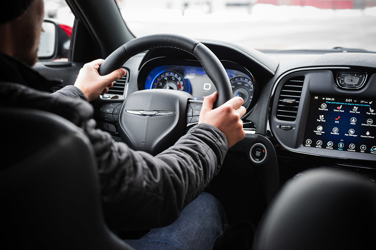 A rear view of a driver in the 2021 Chrysler 300 holding the leather-wrapped steering wheel with both hands.