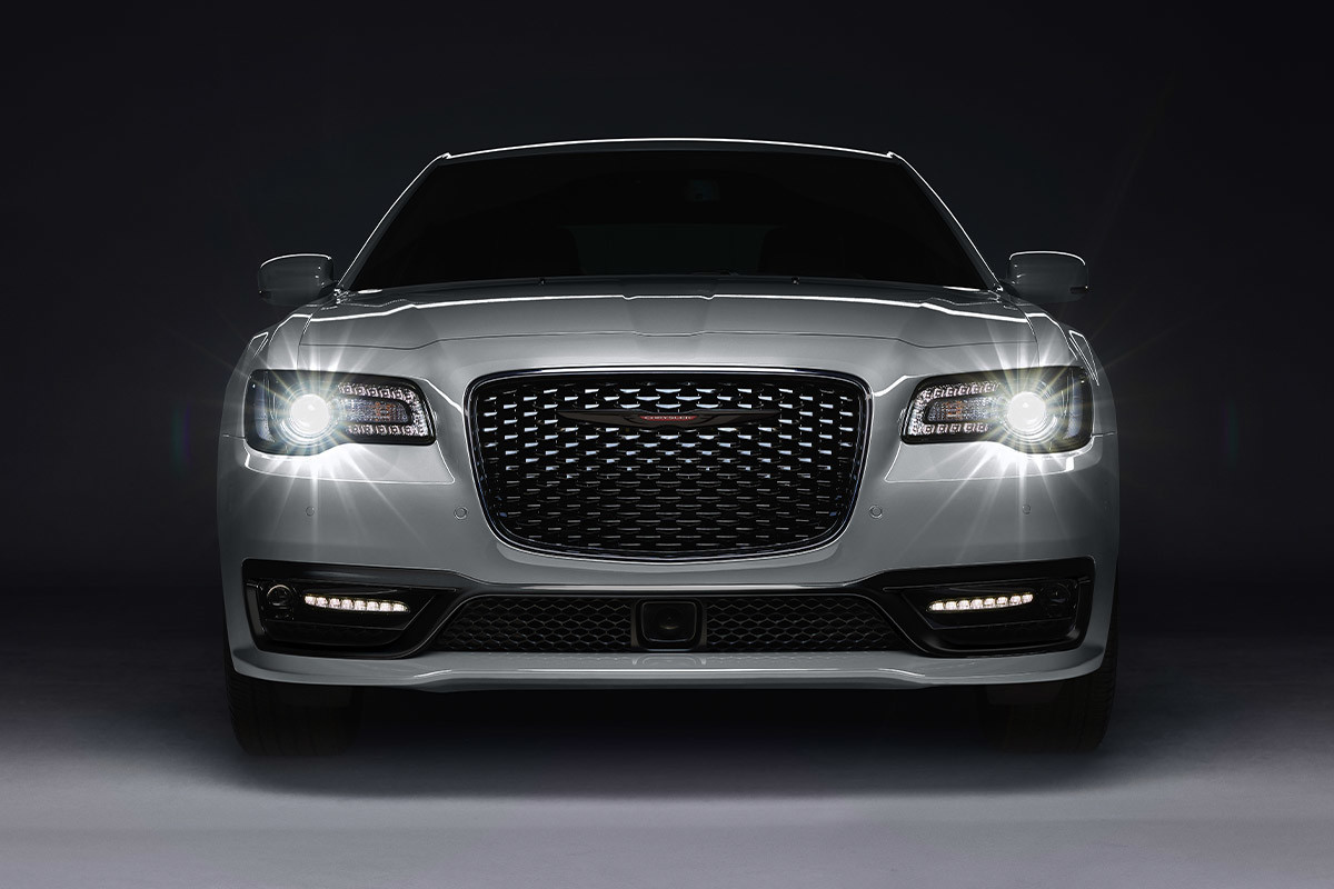 Vue de face d’une Chrysler 300 2021, illustrée en argent, avec les phares allumés.