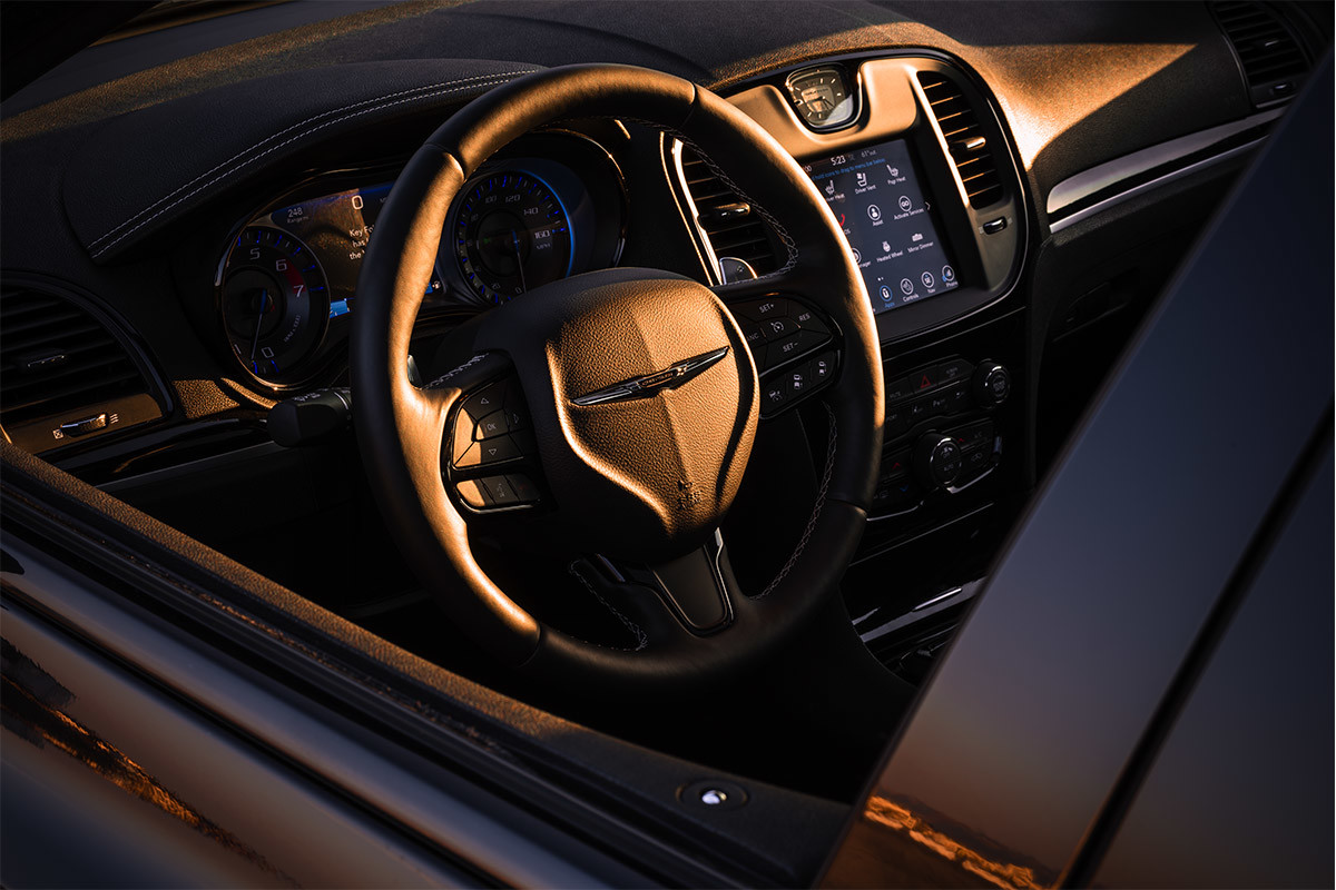 Gros plan du volant gainé de cuir de la Chrysler 300 2021, qui reflète la lumière du soleil.