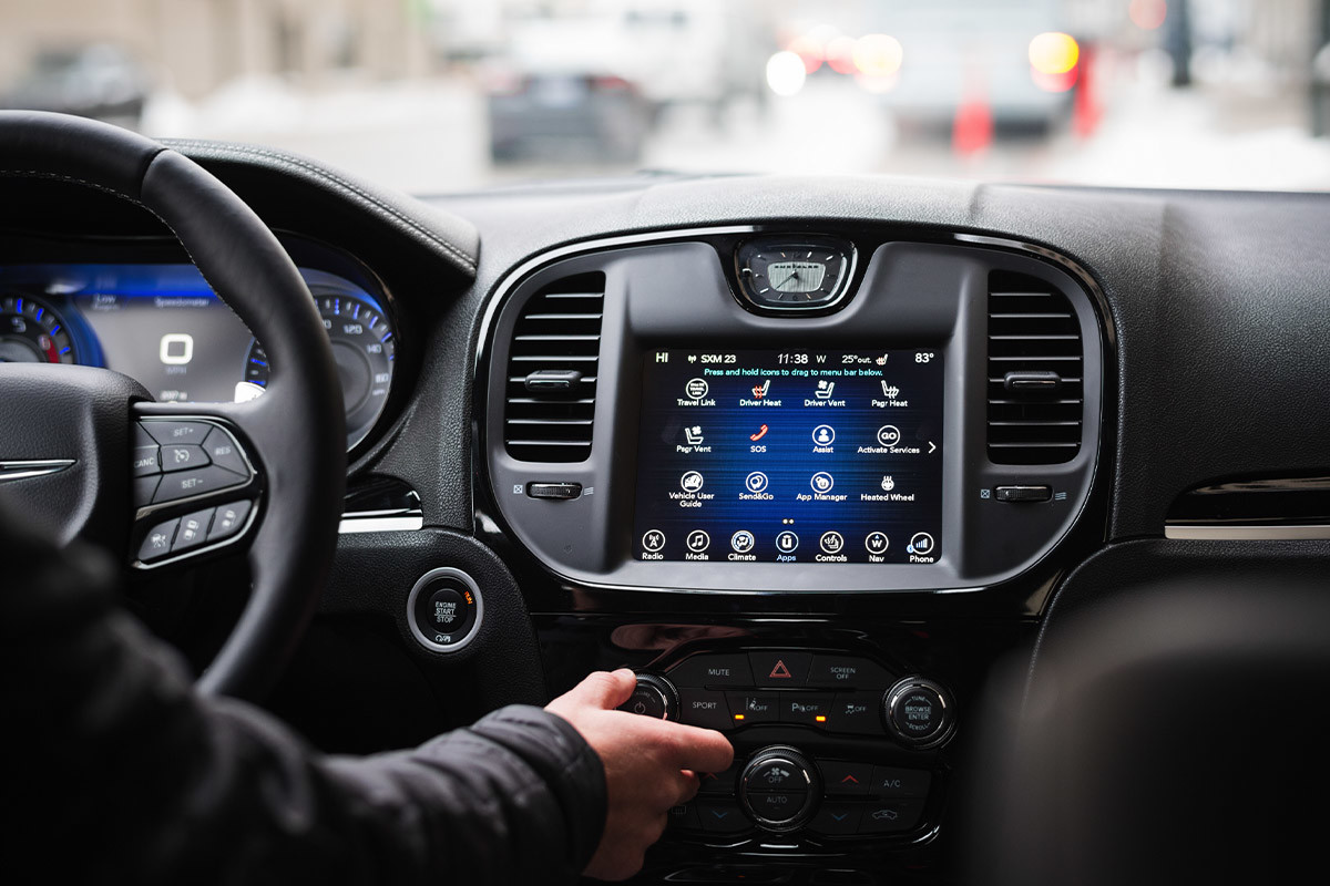 Gros plan d’un conducteur dans la Chrysler 300 2021 réglant les commandes de confort sous le système multimédia Uconnect 4C à écran tactile de 8,4 po.