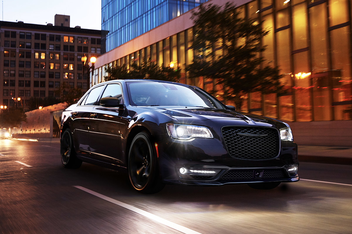 Une Chrysler 300 noire roulant dans les rues de la ville au coucher de soleil