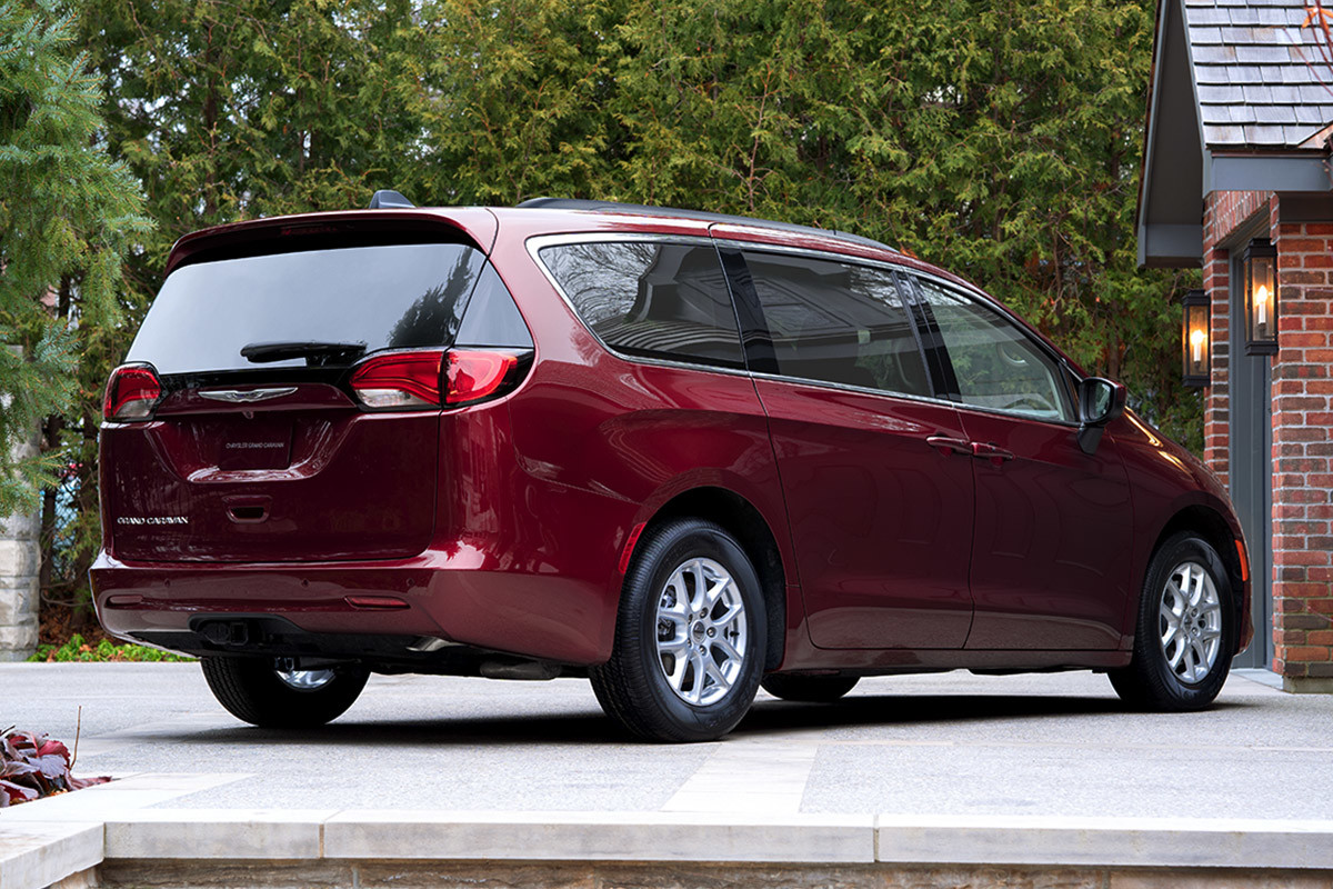 A side view of the contoured exterior of a Velvet Red Pearl 2021 Chrysler Grand Caravan parked on the driveway of a bungalow.