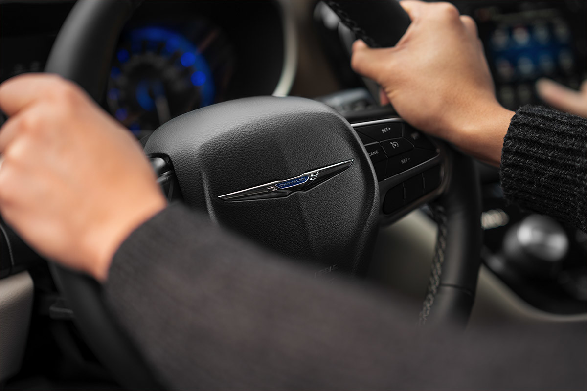 A close-up of a driver holding the steering wheel of the 2021 Chrysler Grand Caravan.