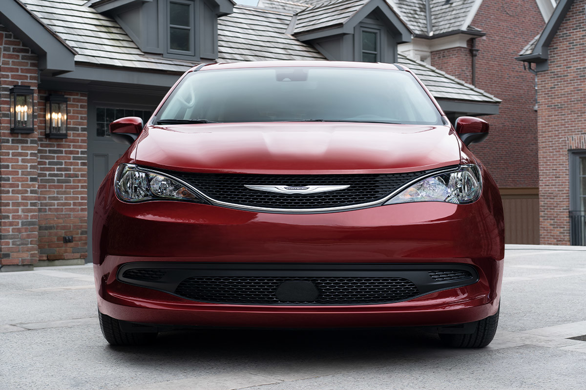 Vue de face d’une Chrysler Grand Caravan rouge stationnée dans une entrée